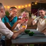 A group of friends with cocktails at a table at night.