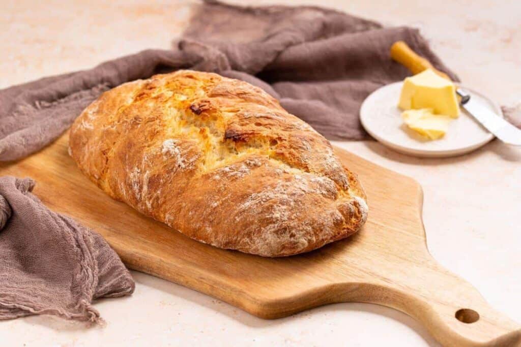 Loaf of artisan bread on wood cutting board.
