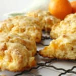 Orange scones on a wire rack with oranges in the background.