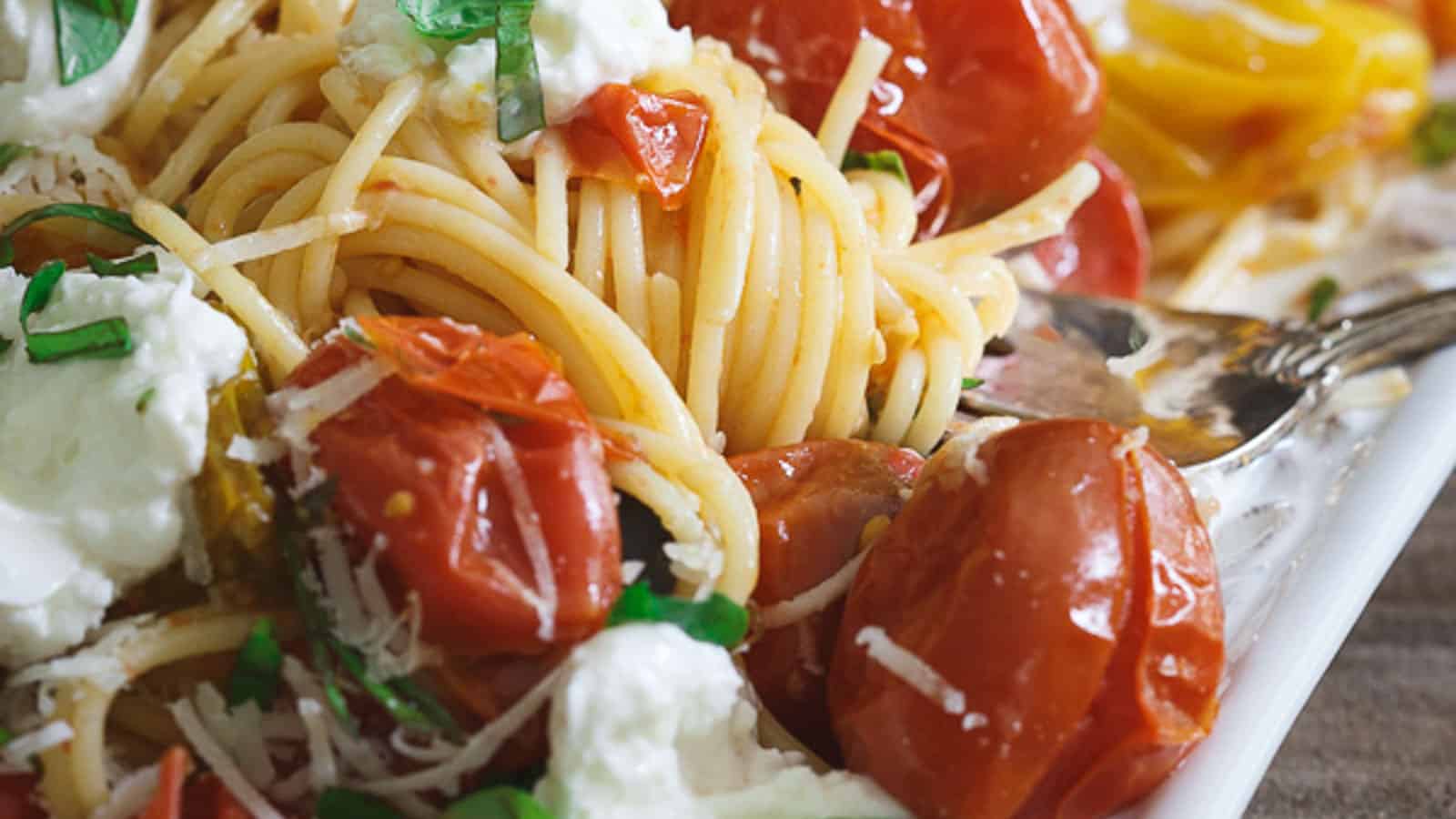 Pasta Checca with burst tomatoes and burrata on a white serving platter.