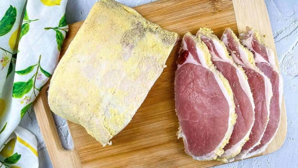 Overhead view of homemade peameal bacon on a cutting board.