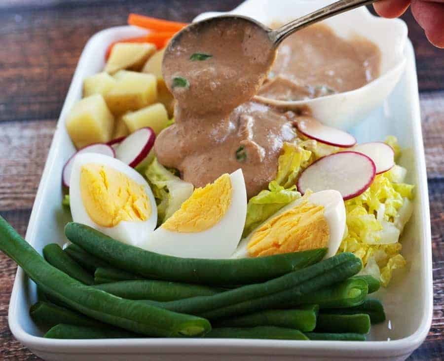 Spooning thai peanut sauce over salad.