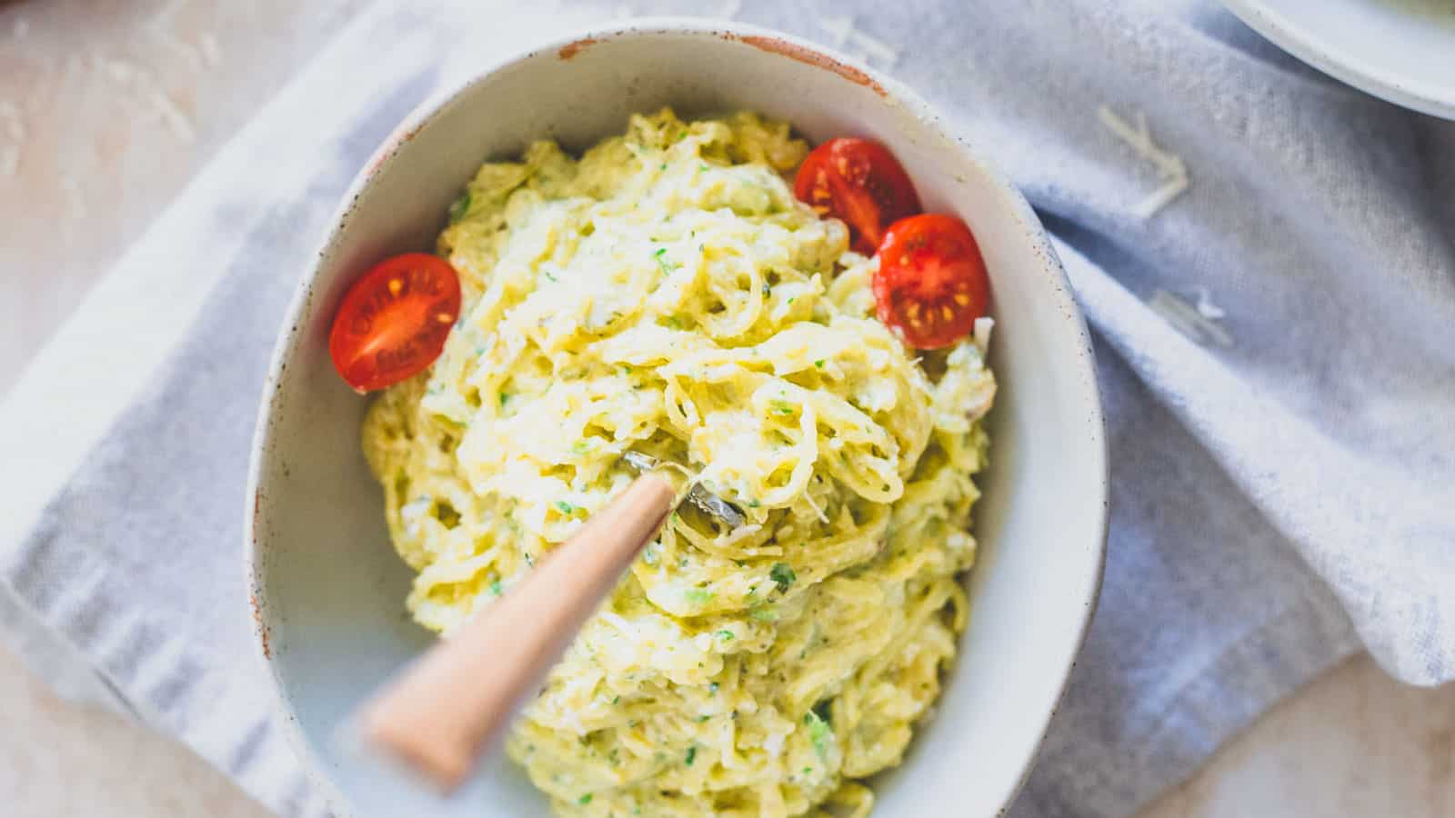 Pesto spaghetti squash noodles in a bowl with cherry tomatoes.