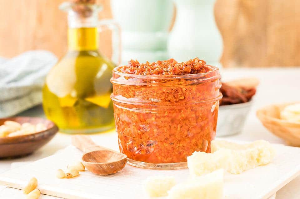 A small mason jar full of red pesto sauce.