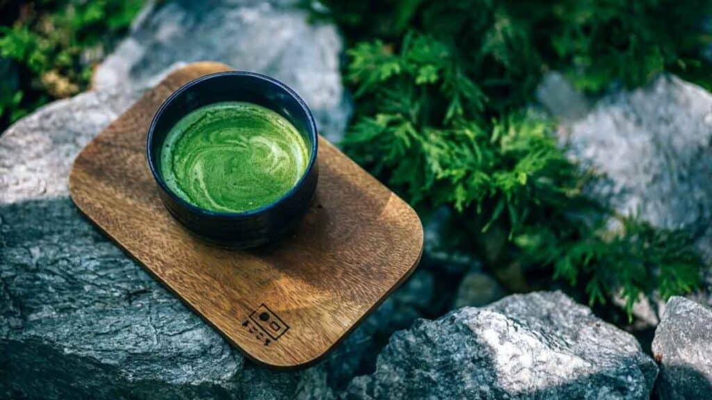 Cup of matcha on a wooden board in the woods. 