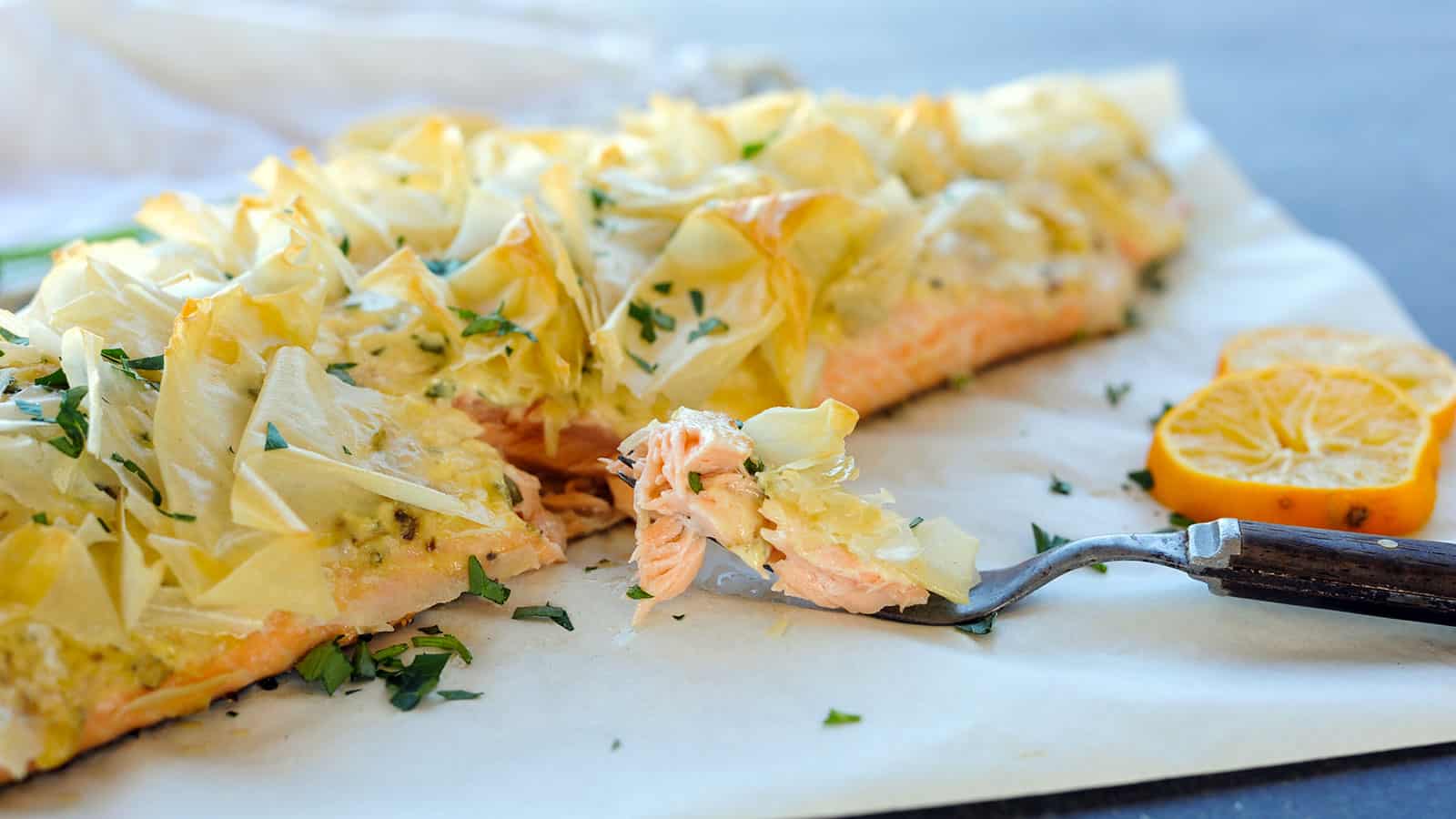 Fork taking bite out of Phyllo Topped Crispy Grilled Salmon.