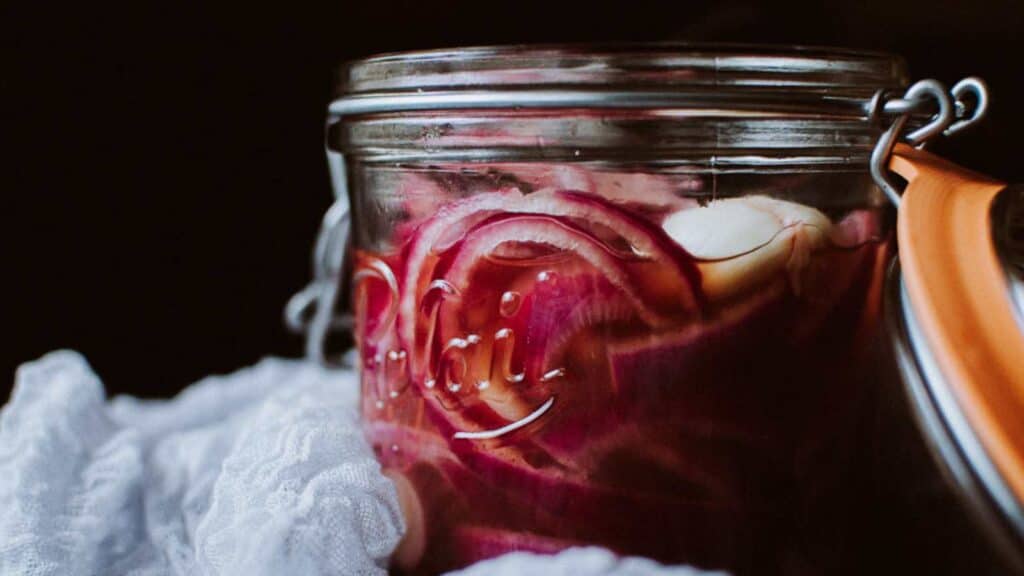 A large clear jar filled with pickled onions.