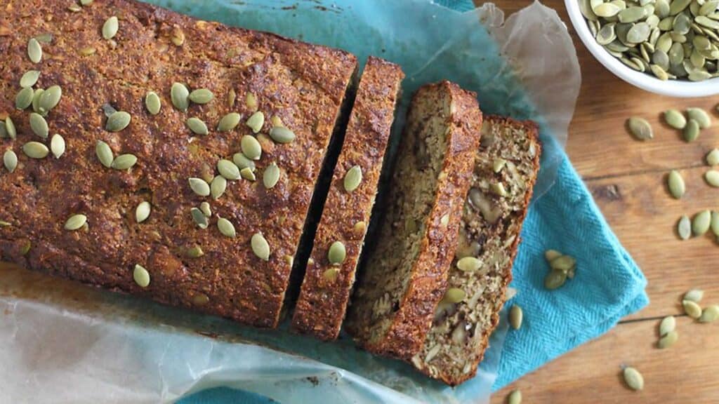 Pumpkin seed nut bread on a blue kitchen towel.