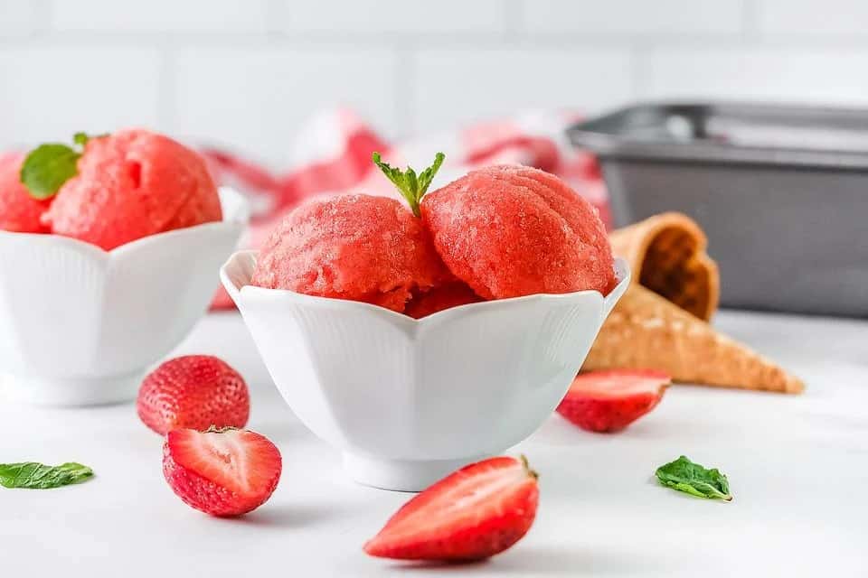 Scoops of strawberry sorbet in a white bowl.