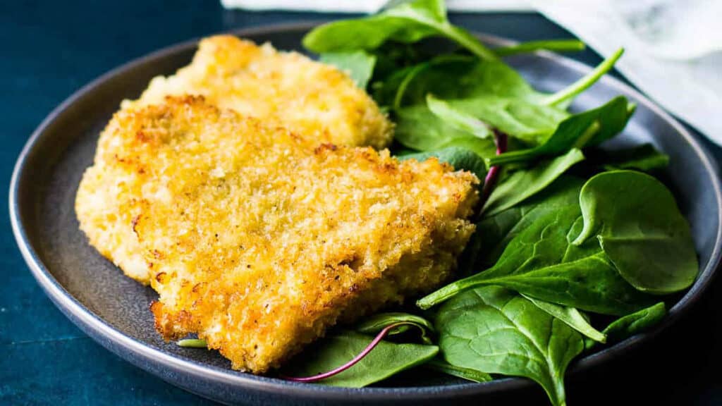panko crusted rockfish on a plate with spinach.