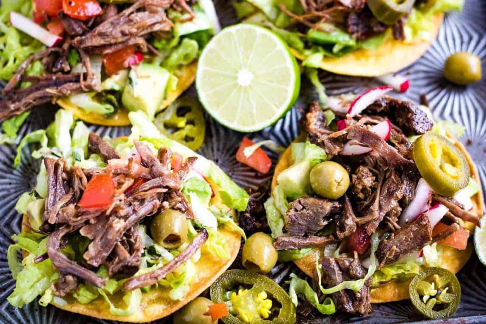 Low angle shot of mini tostadas with salpicon de res or shredded beef salad on top.