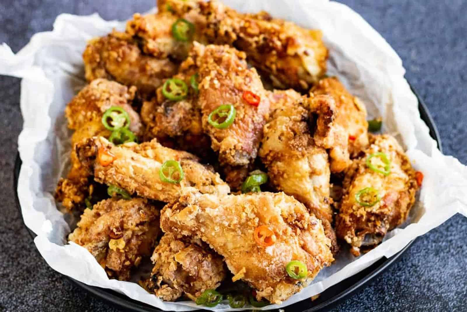 Salt and pepper fried chicken in a bowl lined with parchment paper.