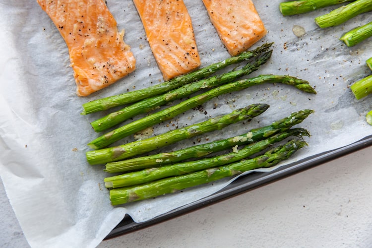 Sheet pan salmon and asparagus cooked on top of parchment paper.
