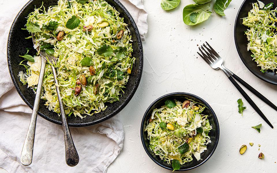 Overhead view of a shaved brussel sprout salad on plates.