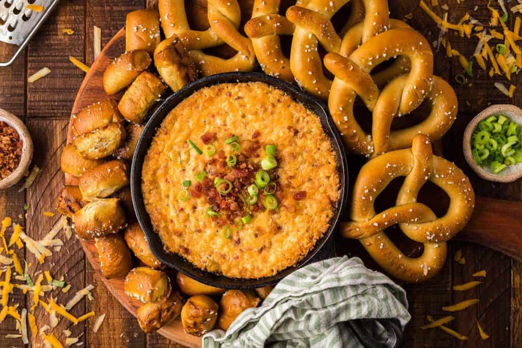 Overhead view of a bowl with cheese dip and pretzels on the side.