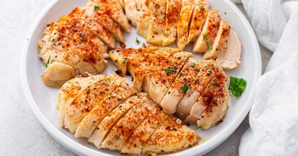 air fryer chicken breasts sliced and on a white plate.