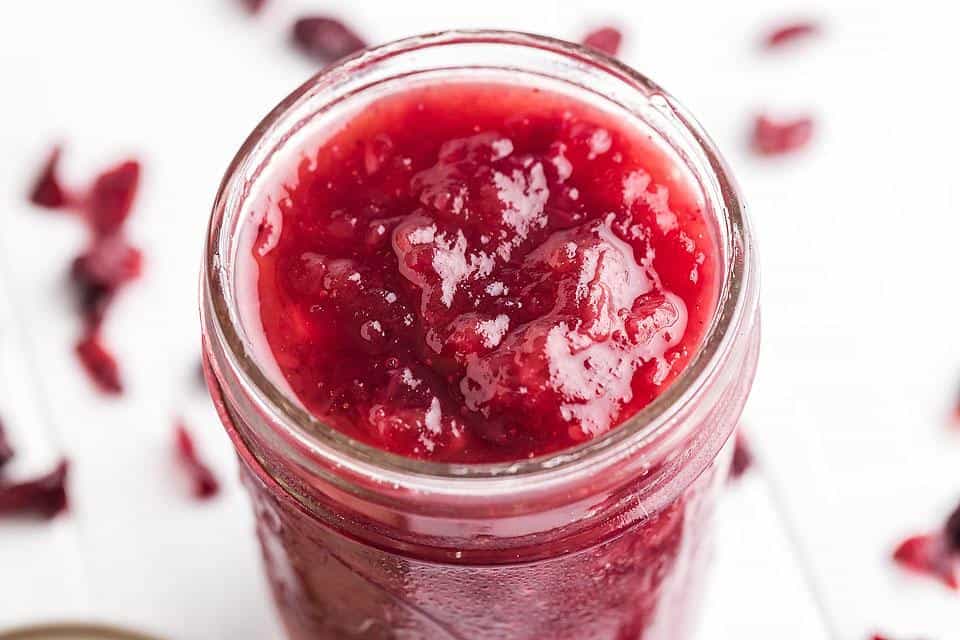 A small mason jar filled with homemade cranberry sauce.