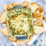 Spinach & Brie Dip in a casserole dish surrounded by pita wedges.