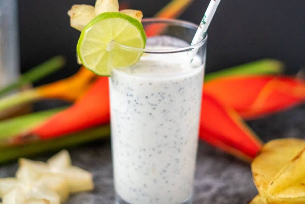 star fruit smoothie in a tall glass with a straw and sliced lime on the rim