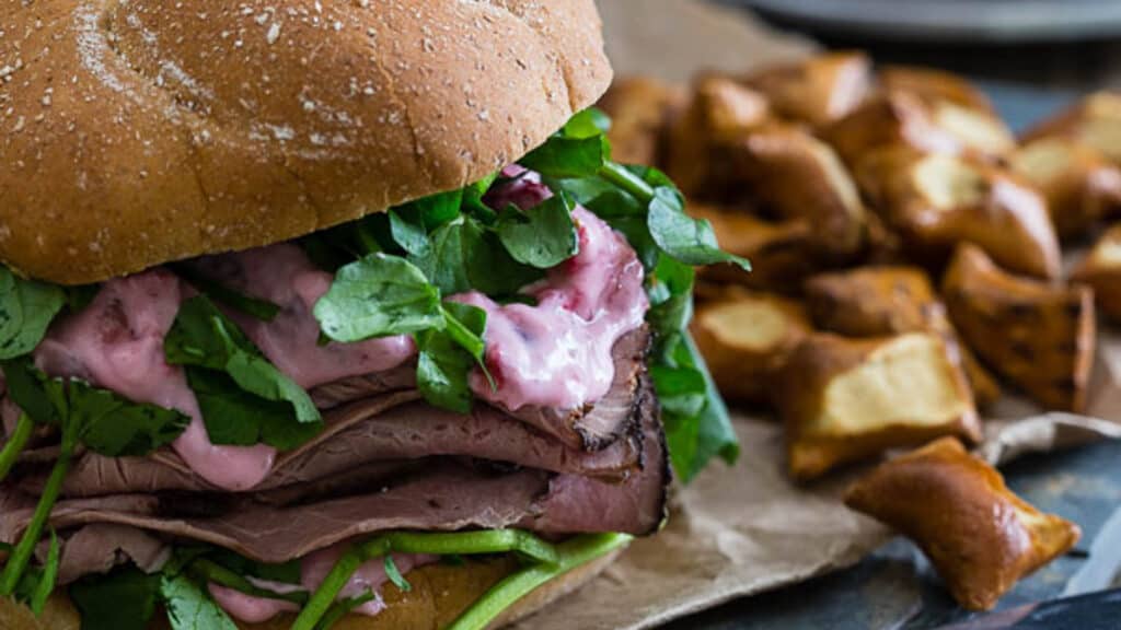 Strawberry goat cheese roast beef sandwich on a bun.