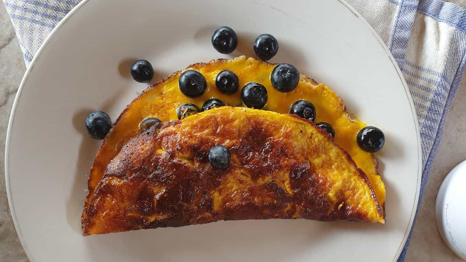 Healthy Sweet Omelette with Blueberries on white plate with napkin.