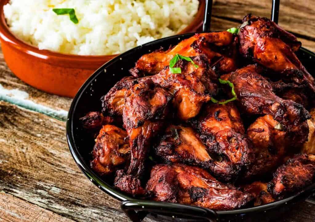 A plate of tandoori chicken with a side dish of cooked rice, shot from a low angle.