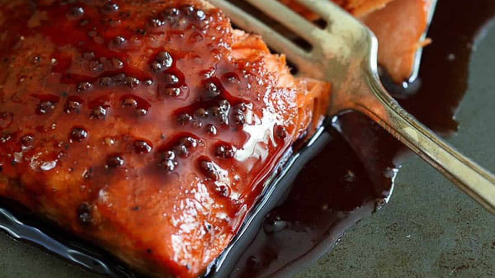 Cherry glazed salmon filet on a baking sheet with a fork.