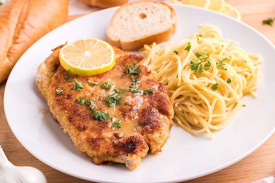 A plate with breaded chicken and spaghetti.