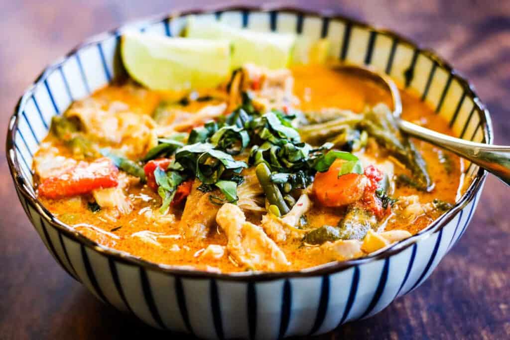 low angle shot of a blue and white striped bowl filled with Thai chicken curry.