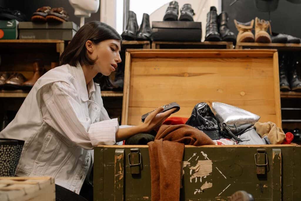 A woman looking through items in a trunk at a thrift store.
