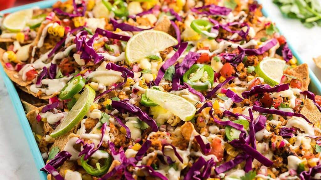 sheet pan nachos with cheese, veggie and lime.