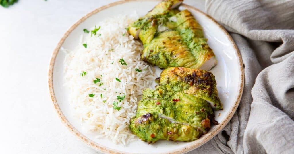 Trader Joe's pesto chicken on a plate with rice and a grey napkin.