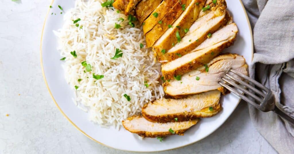 Trader Joe's Shawarma chicken thighs on a white plate with rice and a fork.