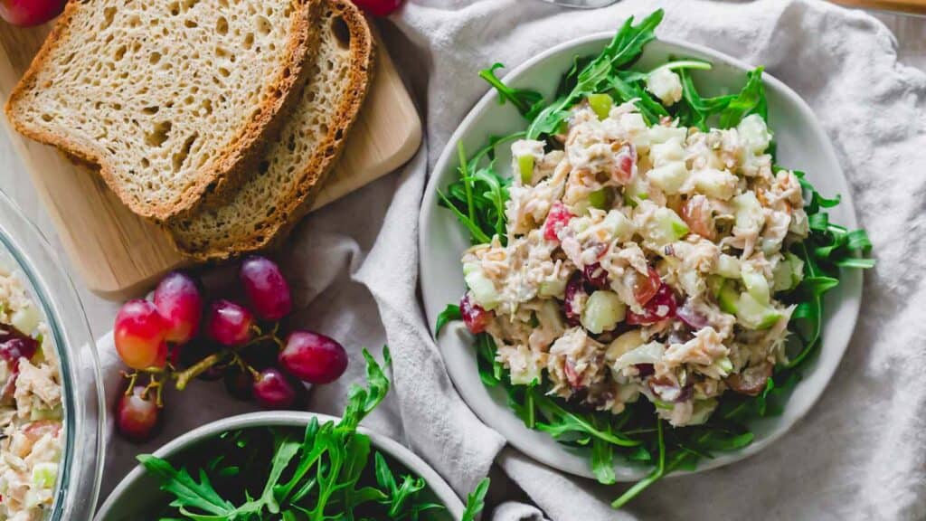 Tuna Waldorf salad on baby greens with bread and grapes on the side.