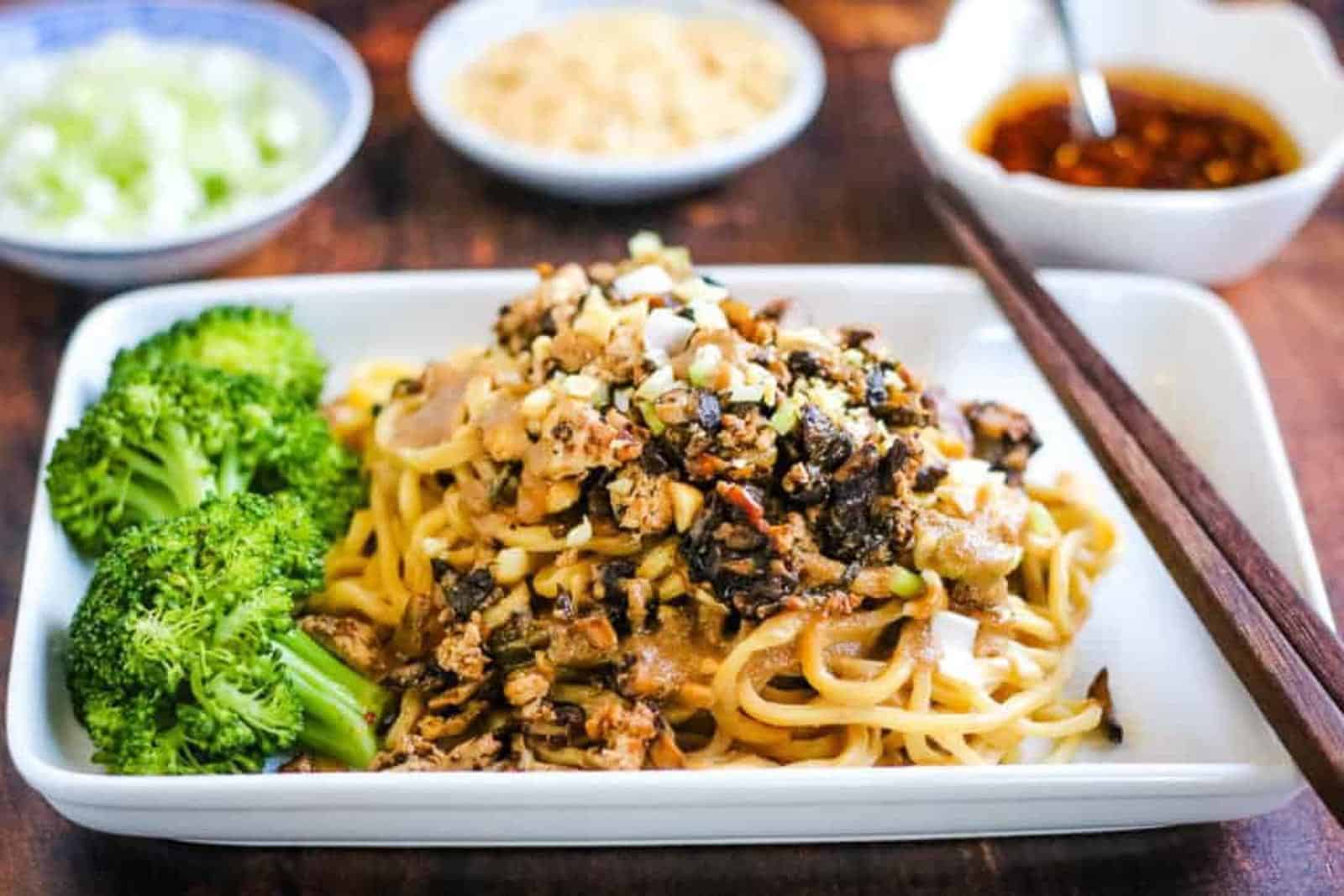 Dan dan noodles with broccoli and chopsticks.