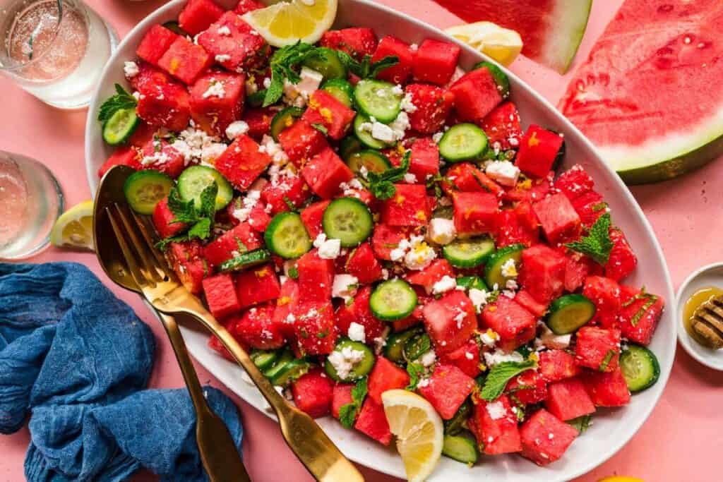 Overhead view of a watermelon feta cucumber salad on a large platter. 