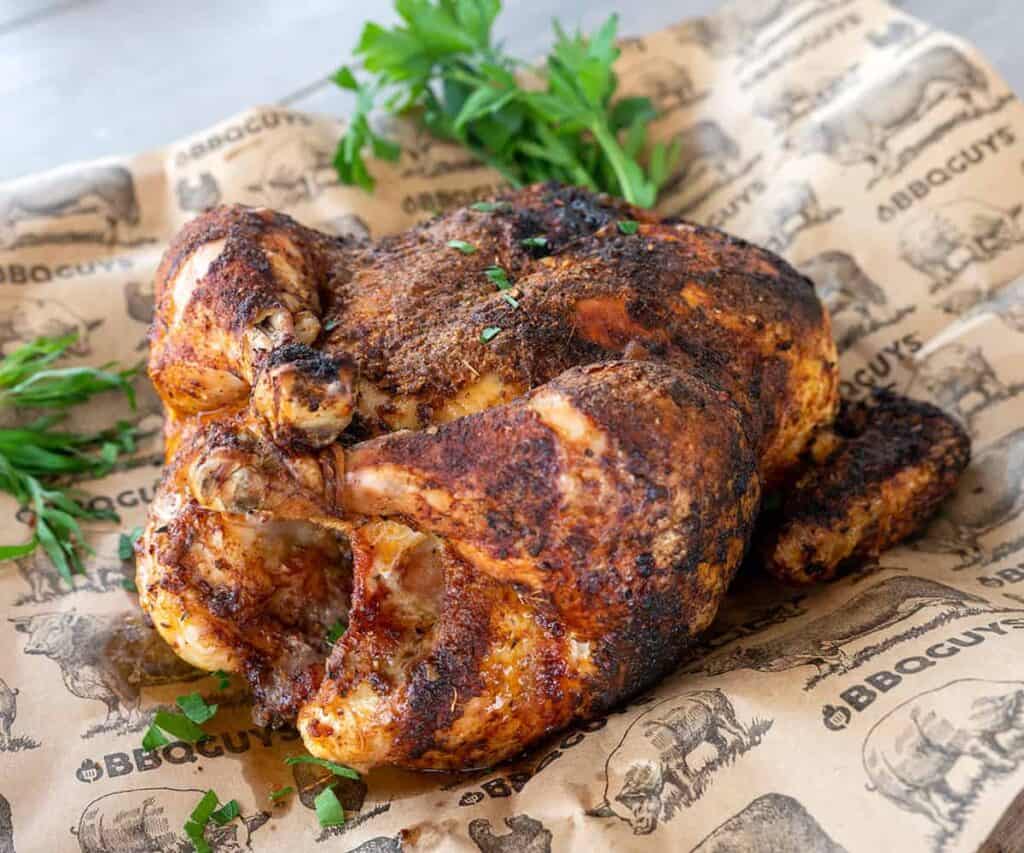 Whole chicken on brown paper with parsley garnish.