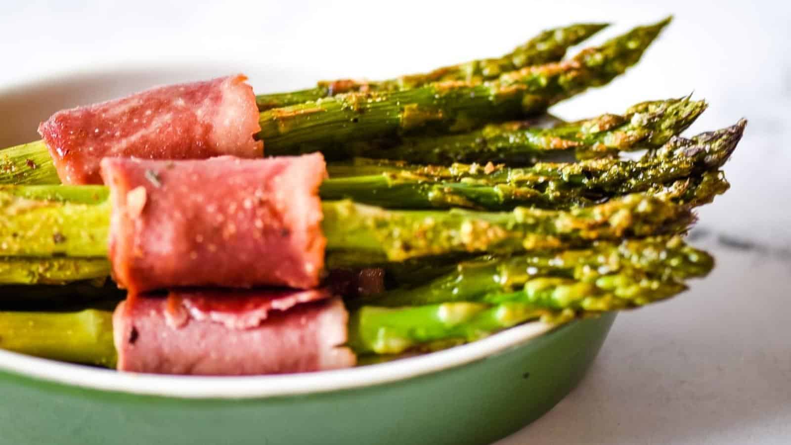 Turkey bacon-wrapped asparagus in a green dish.