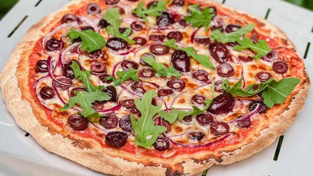 Olive pizza on a pizza peel.