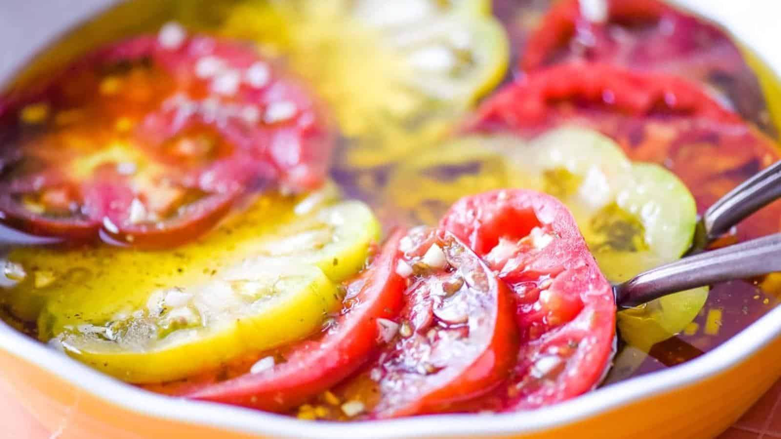 Closeup of marinated heirloom tomatoes in a yellow and white pie dish.