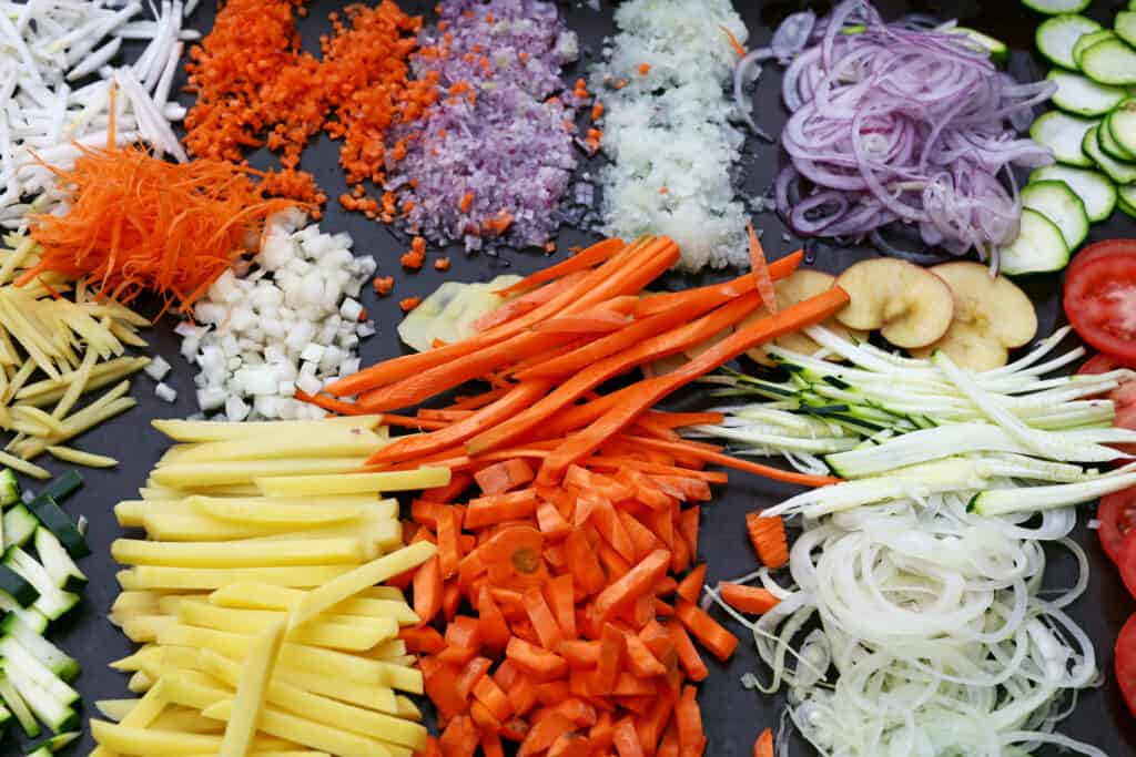 An assortment of vegetables displaying different knife cuts: slice, mince, dice, chiffonade, julienne, batonnet. 