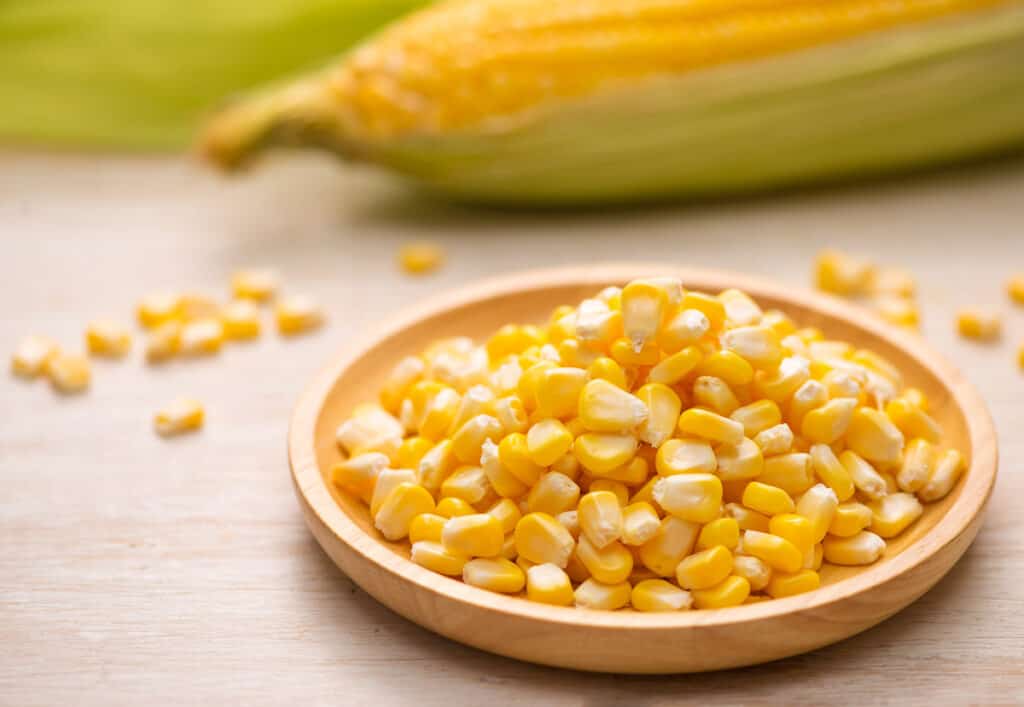 Sweet corn kernels on a wooden plate.