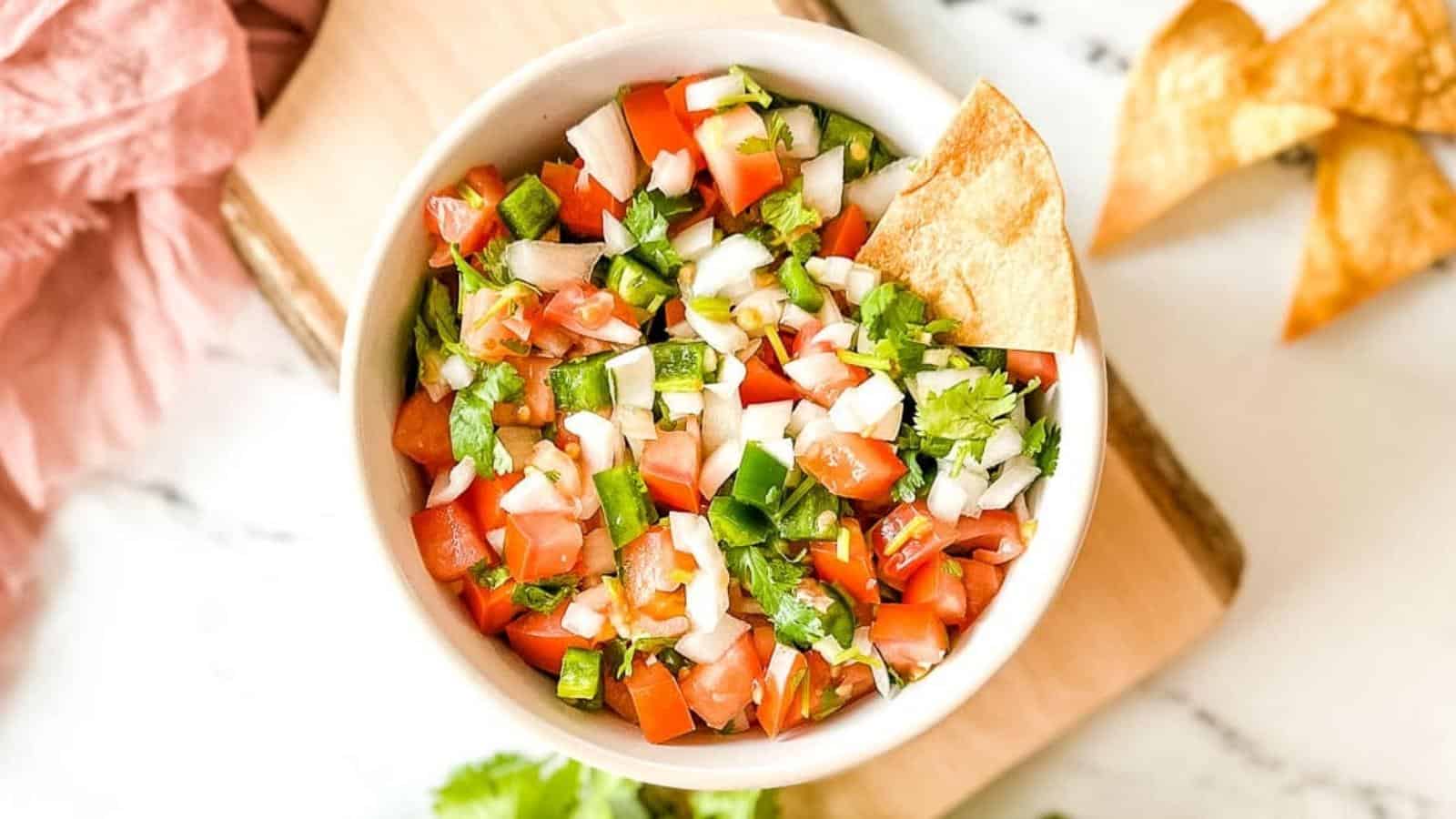 Pico de Gallo in a white dish with a tortilla chip.