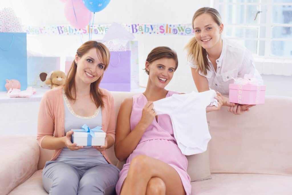 A young pregnant woman receiving gifts from her pretty friends at her babyshower.