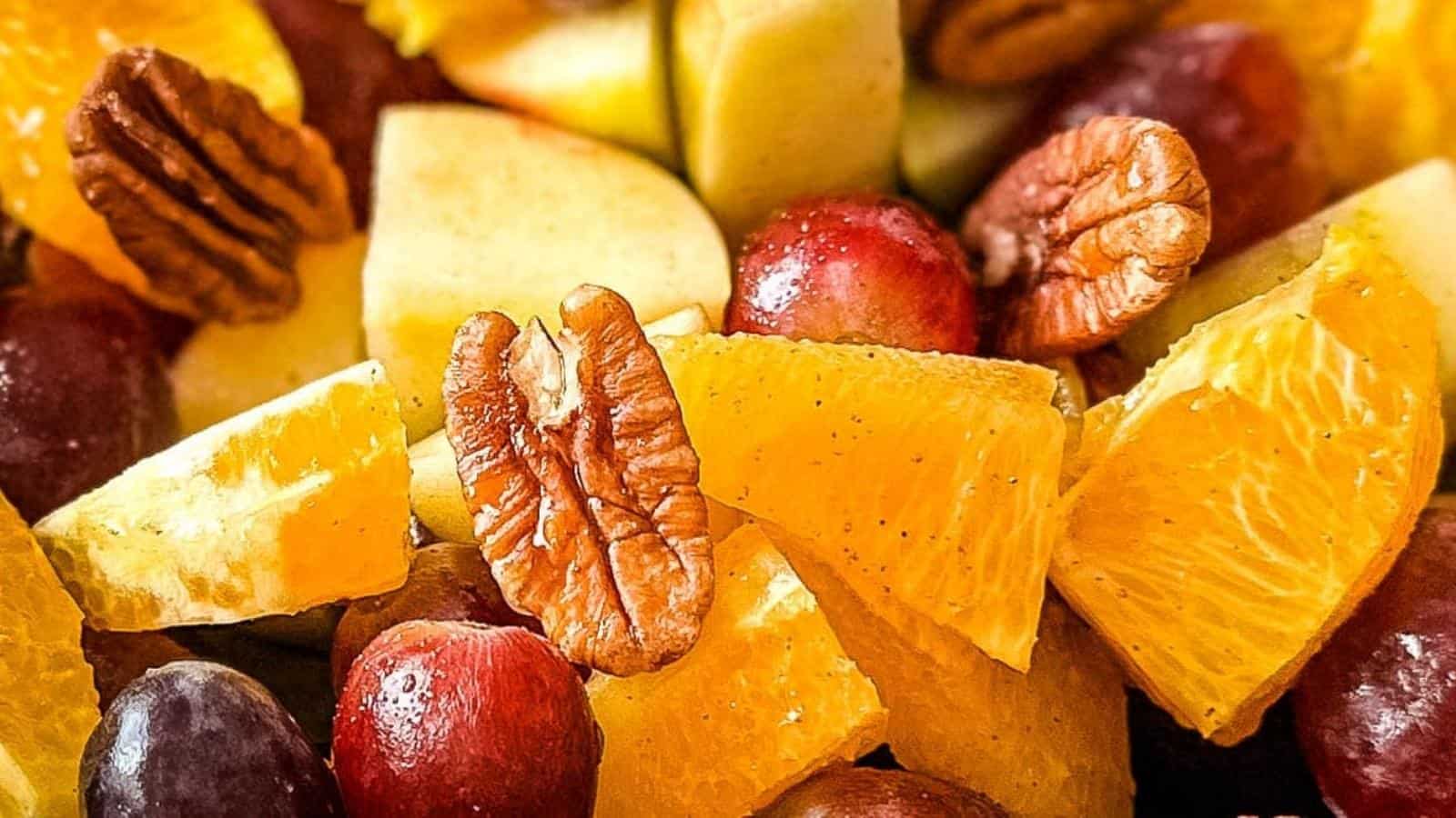 A closeup is shown of Thanksgiving Fruit Salad with apples, grapes, pears, oranges, and pecans.