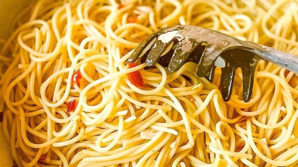 Closeup of noodles coated in olive oil with chili flakes.