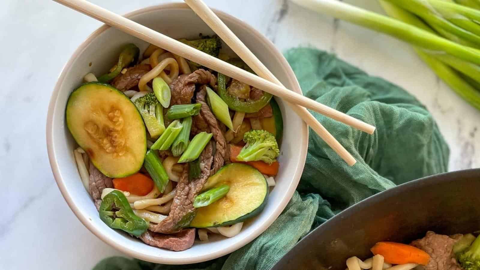 Beef yaki udon in a white bowl with chopsticks.