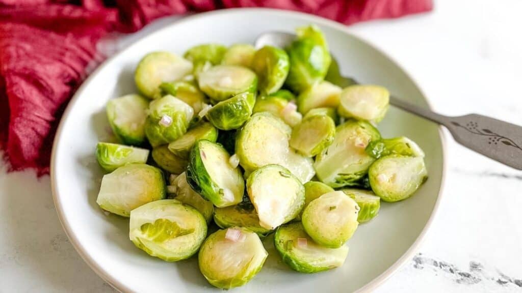 Marinated Brussels sprouts on a white plate with a silver fork.