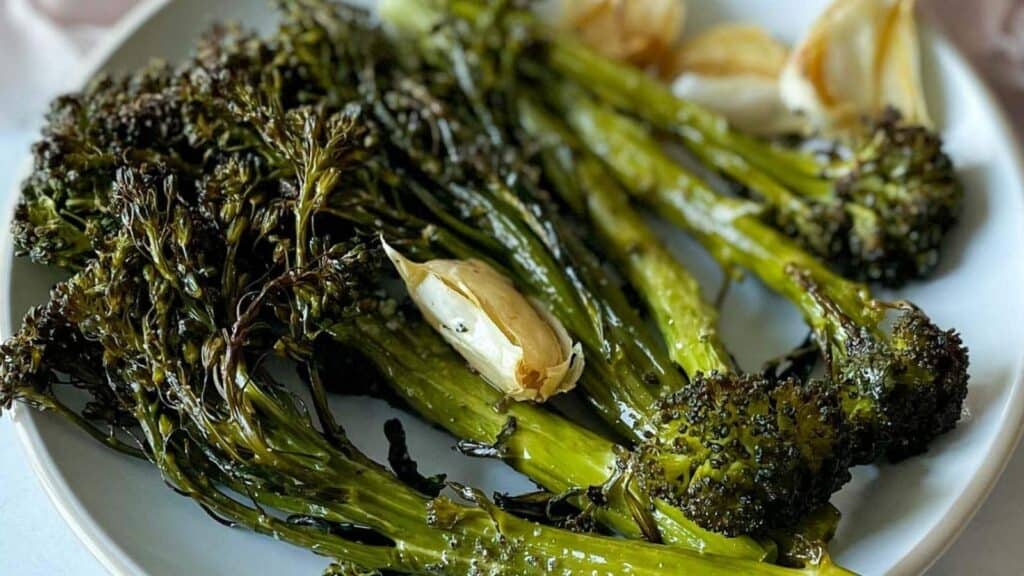Roasted broccolini on a white plate with garlic.
