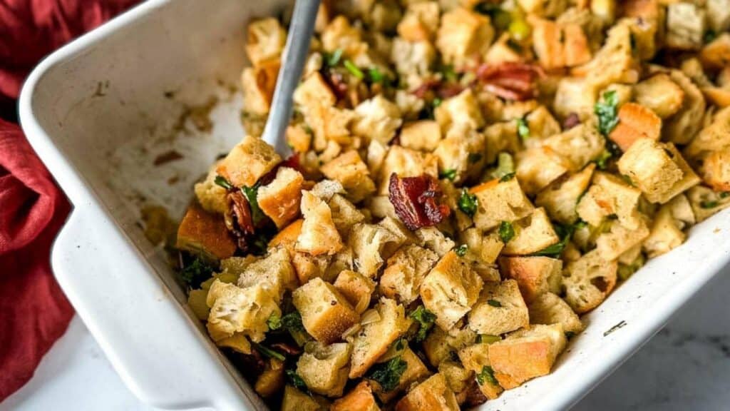 Sage and bacon stuffing in a white baking dish.